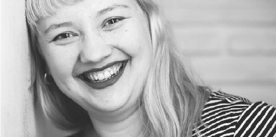 Schwarz-weiß Bild von Katharina Dieckmann. Sie schaut gerade in die Kamera und lacht.